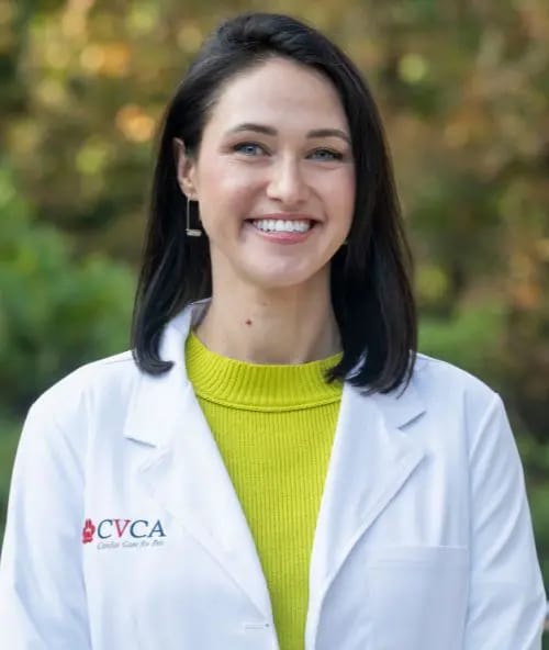 Smiling woman with a dark bob in a white coat and a bright yellow-green sweater