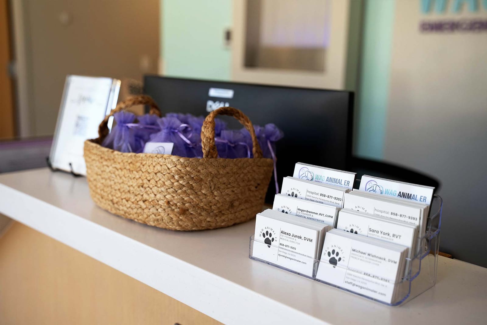 Reception counter with a woven basket of small purple bags and a holder of business cards