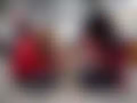 Out-of-focus image with blurred red and dark shapes on a pale grey background