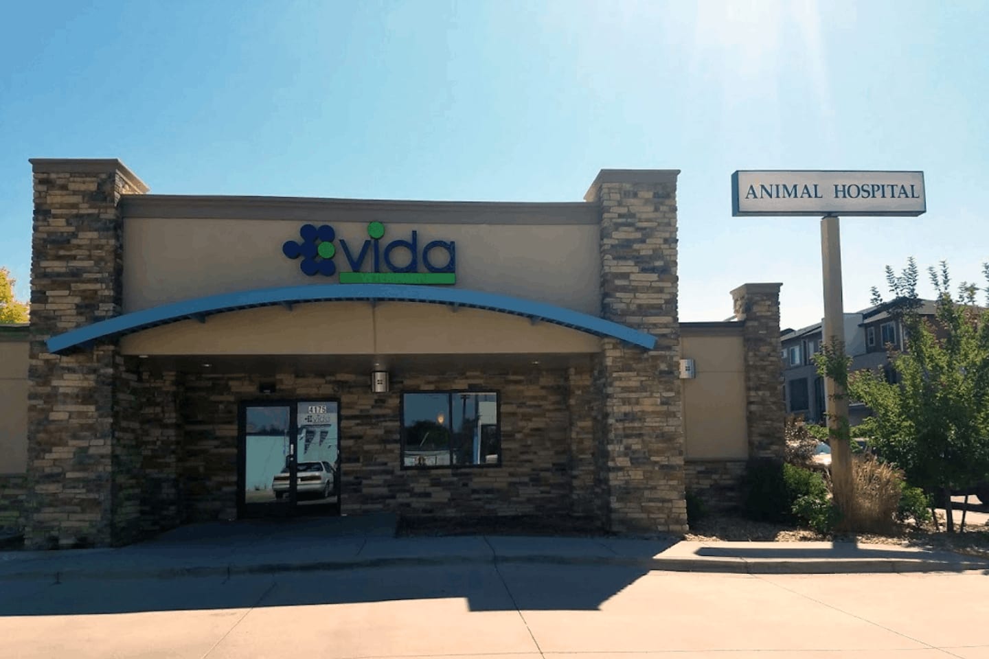 Front of VIDA Veterinary Care in Denver, a stone and tan building with a blue awning and logo