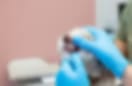 Blurry low-resolution image of blue-gloved hands holding a small animal's head