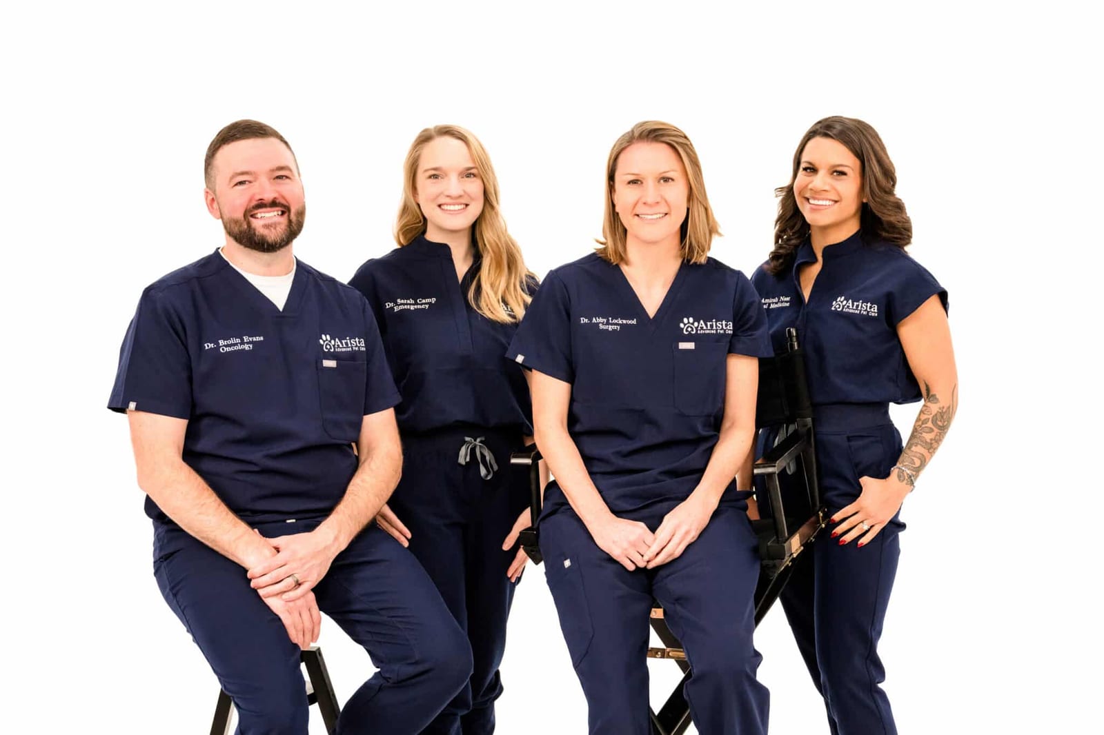 Four people in navy Arista scrubs posing together against a white background