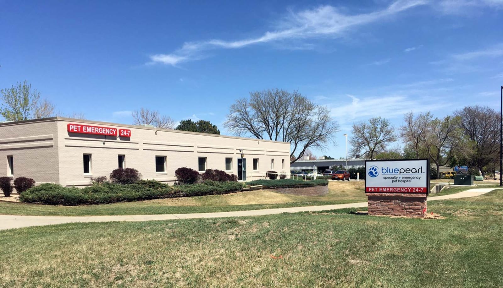 BluePearl building with a brick sign reading Pet Emergency 24/7 beside a path and grass
