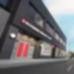 Heavily blurred image of a dark building with a red sign under blue sky