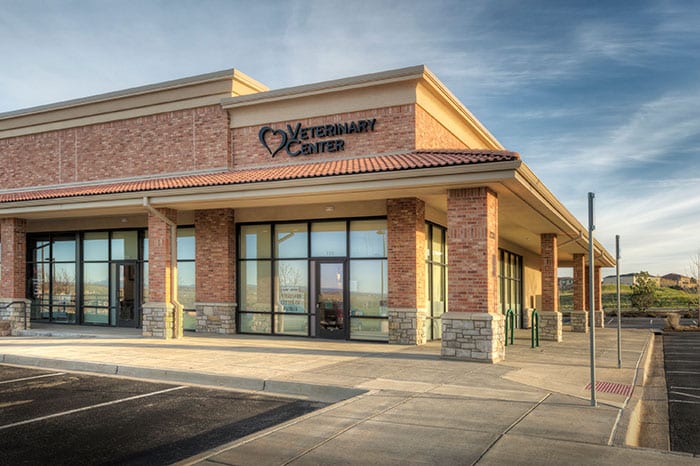 Brick and stone corner building with a tile roof and a heart logo sign at sunset