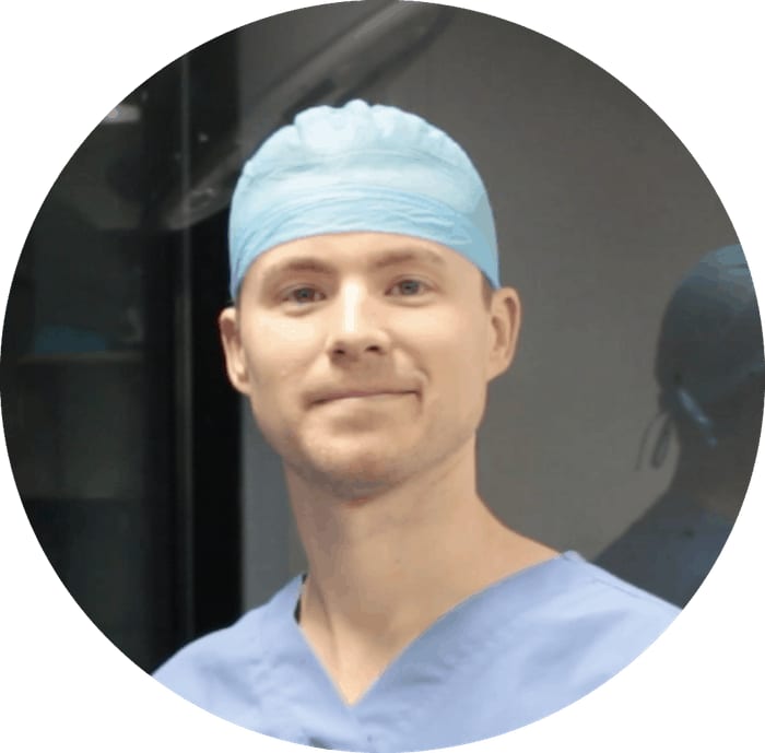 Person in a light blue scrub cap and scrubs in a circular photo