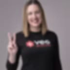 Blurry low-resolution image of a smiling woman in a black top holding up two fingers