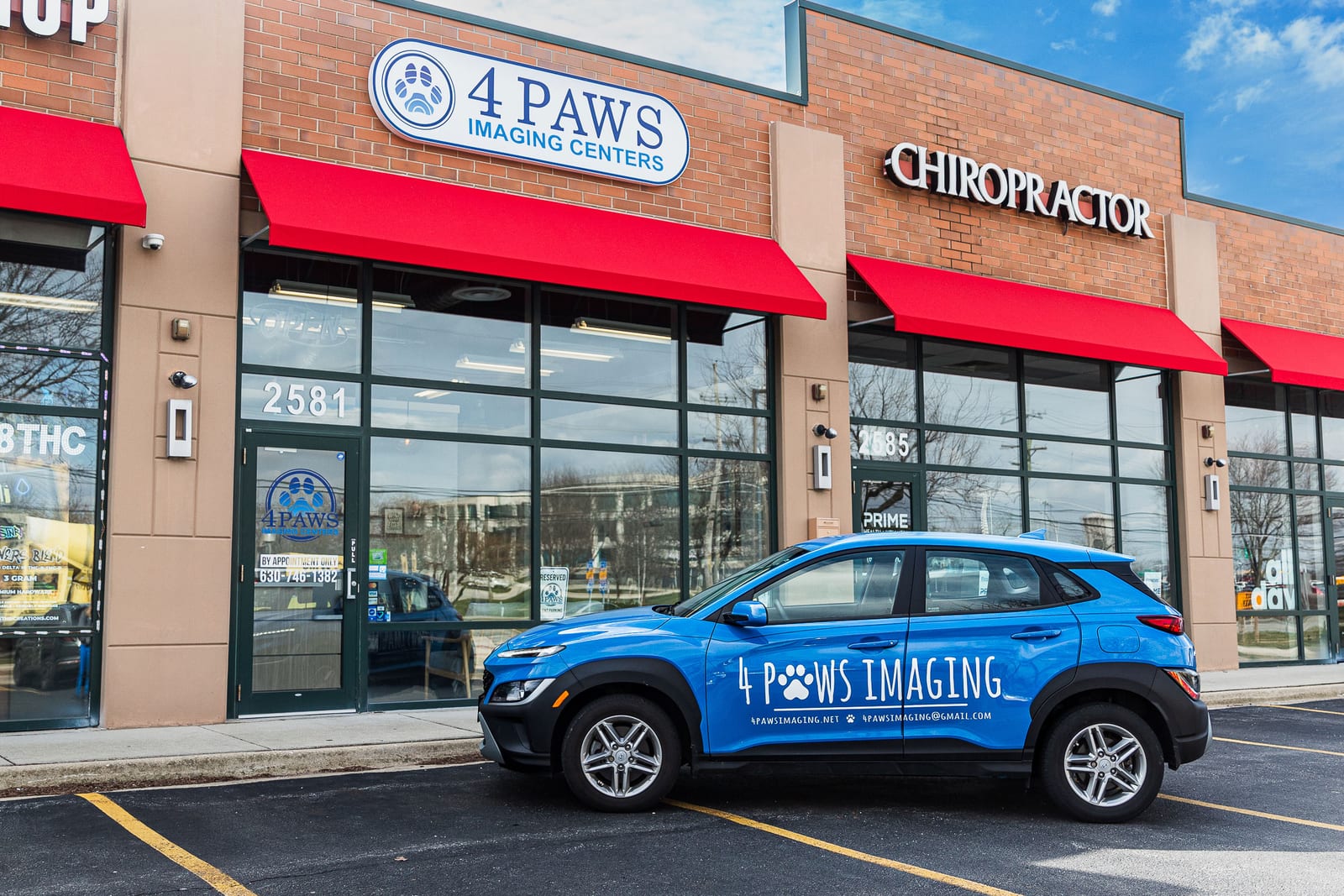 4 Paws Imaging Centers storefront with red awnings and a blue lettered car parked in front