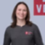 Very small blurry image of a smiling woman in a dark gray sweater against a pale blue background