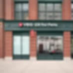 Very small blurry image of a red brick storefront with green trim and glass doors