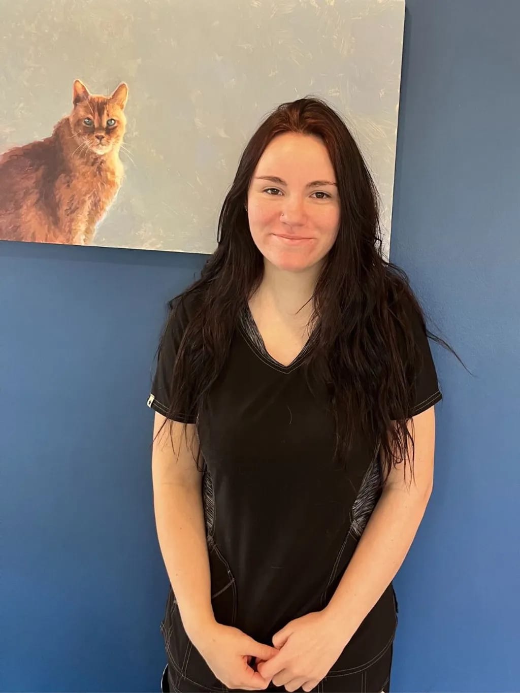 Staff member in a black top standing in front of a blue wall at Southdale Pet Hospital