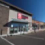 Blurry low-resolution photo of a strip-mall storefront with a dark awning under a blue sky