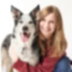 Low-resolution photo of a woman with long hair hugging a black and white dog on a white background