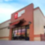 Very blurry image of a tan brick building with a red sign over a glass storefront