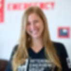 Blurry low-resolution portrait of a smiling woman with long blonde hair in a dark top