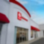Very blurry image of a white building with a red curved roof band and glass doors