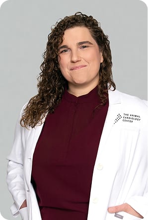 Woman with long curly brown hair in a white coat over a maroon top