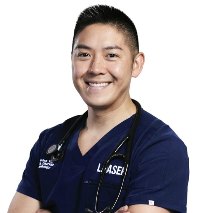 Smiling man with short dark hair in navy scrubs with arms crossed and a stethoscope