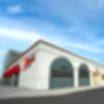 Very small blurry image of a cream building with arched windows and a red awning