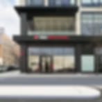 Very small blurry image of a storefront with a dark facade and red sign on a city street