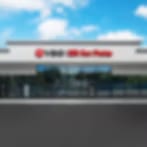 Very small blurry image of a single-storey storefront with a red sign under a blue sky