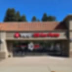 Very small blurry image of a single-storey building with a brown roof and red sign