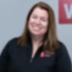Blurry low-resolution portrait of a smiling woman with long brown hair in a dark top
