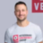 Blurry low-resolution portrait of a smiling man with short dark hair in a light grey T-shirt