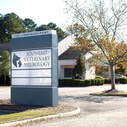 Southeast Veterinary Neurology monument sign with a dog and cat logo in front of a low building