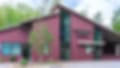 Low-resolution image of a building with red-brown walls partly hidden by green trees